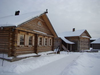 Houses on snow covered field by building against sky