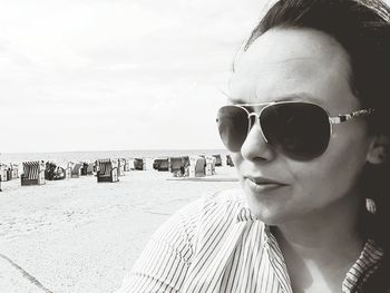 Close-up of woman in sunglasses at beach against sky