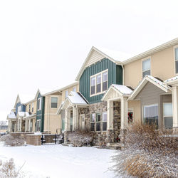 Houses by buildings against clear sky during winter