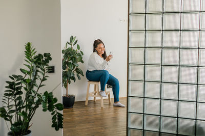 Full length of young woman standing against wall