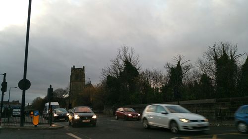Cars on road against cloudy sky
