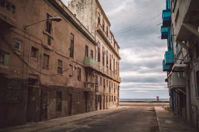 Empty road amidst buildings against sky