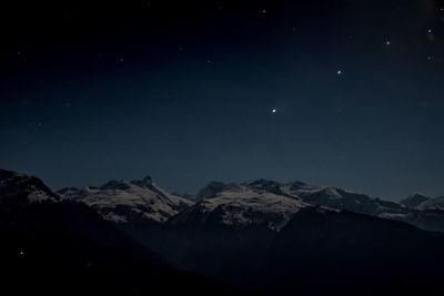 Scenic view of snow covered mountains against sky at night