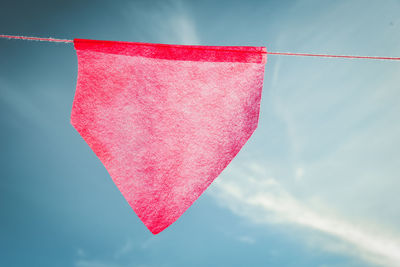 Low angle view of red bunting hanging against blue sky