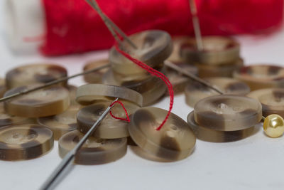 Close-up of buttons and sewing needle over white background