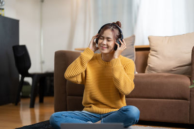 Side view of young woman sitting on sofa at home