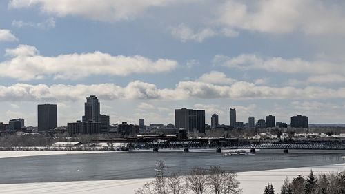 River by city buildings against sky