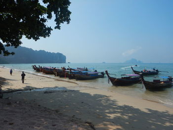 Boats moored on beach against clear sky