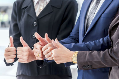 Midsection of colleagues showing thumbs ups on elevated walkway