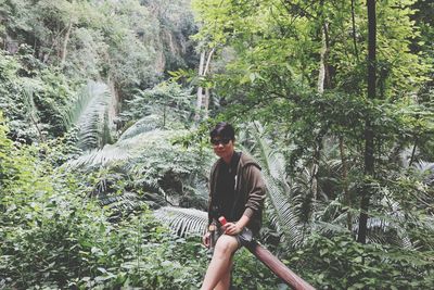 Portrait of woman standing by railing in forest