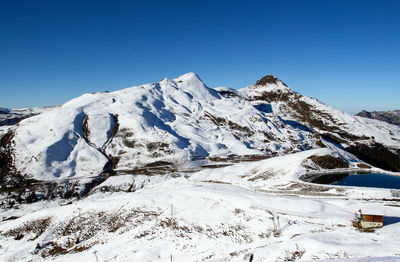 Scenic view of snowcapped mountains against clear blue sky