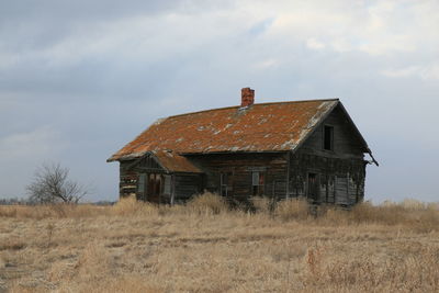 Old house on land against sky