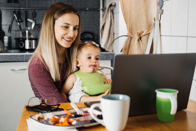 Portrait of mother and daughter holding smart phone on table