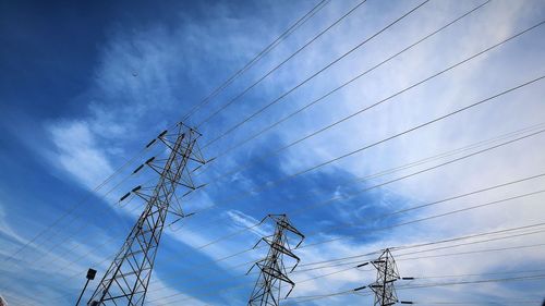 Low angle view of electricity pylons against sky