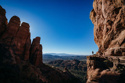 Rock formations with woman standing against sky