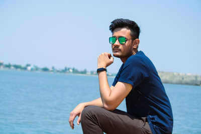 Young man wearing sunglasses against blue sky