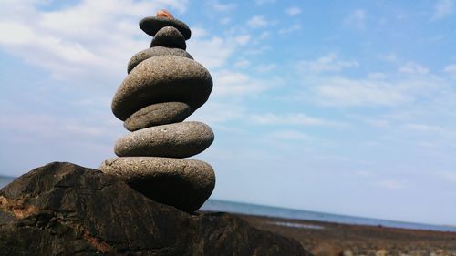 Stacked stones at beach against sky