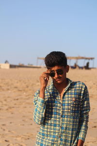 Young man wearing sunglasses standing on beach