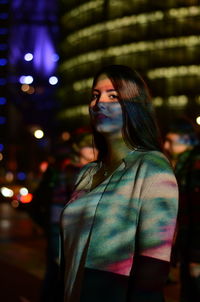 Young woman standing in illuminated city at night