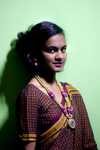 Portrait of smiling young woman against wall