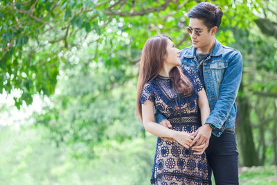 Young couple standing against trees