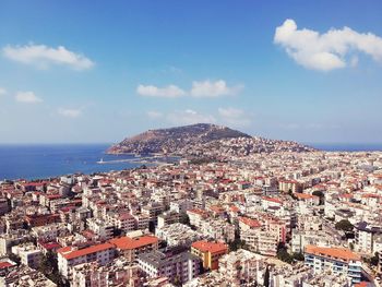 Aerial view of townscape by sea against sky