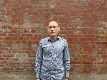 Thoughtful man standing against brick wall