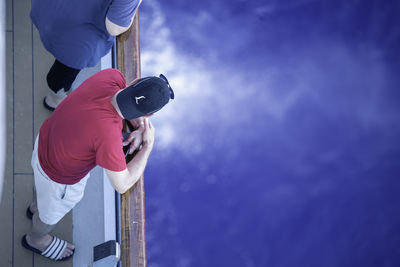 Man holding camera while standing against blue sky