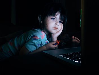 Girl with hand on chin looking at laptop