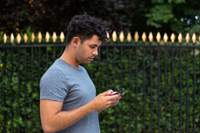 Side view of man using mobile phone outdoors