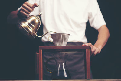 Midsection of man pouring black coffee in mug