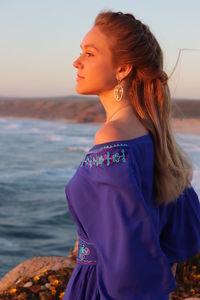 Side view of young woman looking away while standing on beach