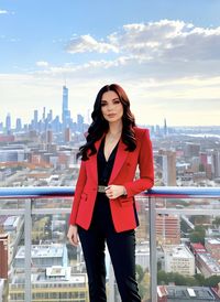 Portrait of young woman standing against cityscape