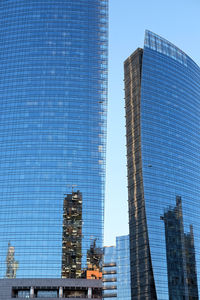 Low angle view of modern glass building against blue sky