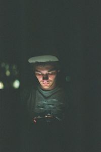 Close-up of young man using smart phone during night