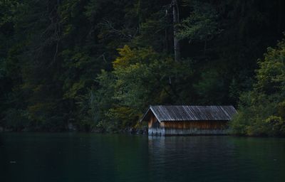 Scenic view of lake by trees and house in forest