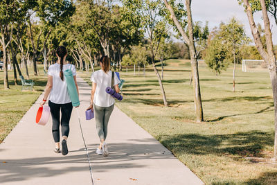 Two young women walking in the morning park, going to exercise outdoors.
