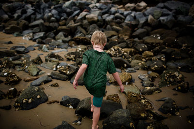 Rear view of woman standing on rocks at beach