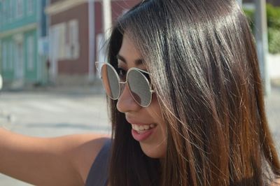 Close-up of smiling young woman wearing sunglasses