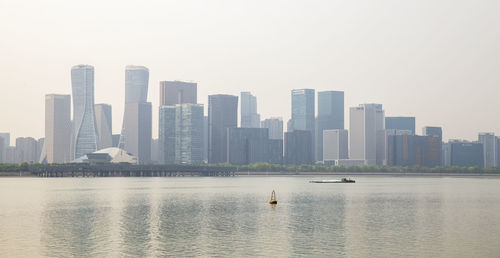 Sea by modern buildings against clear sky