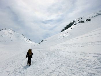 Rear view of man skiing on snowcapped mountain against sky