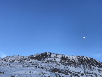 Low angle view of snowcapped mountain against blue sky