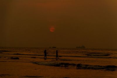 Silhouette person on beach against sky during sunset