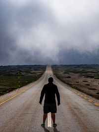 Rear view of man standing on road against sky