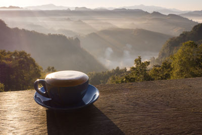 Coffee cup on table against mountains