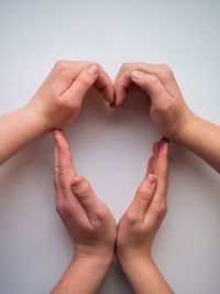 Cropped image of people making heart shape over white background
