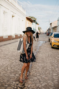 Full length portrait of young woman standing on street in city