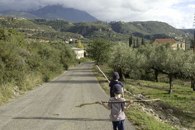 Rear view of  boys walking on road