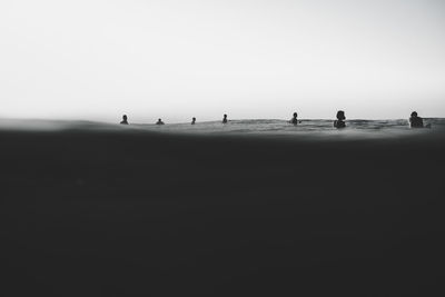 Silhouette people on beach against clear sky