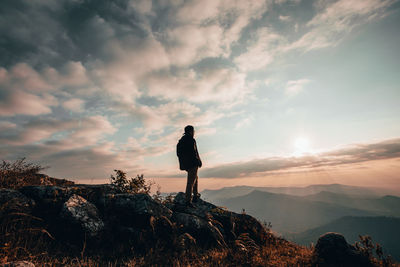 Man standing on rock against sky